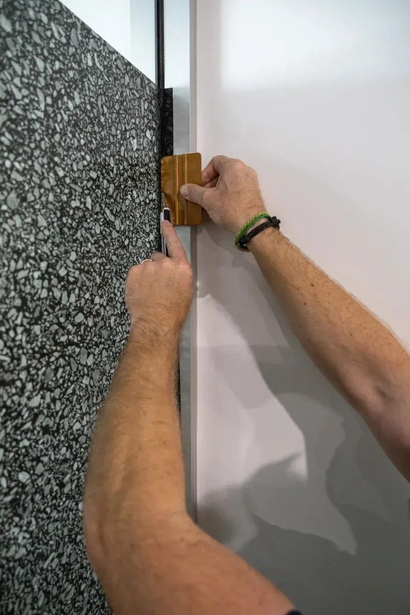 Installer finishing patterned glass film along the edge of a door frame