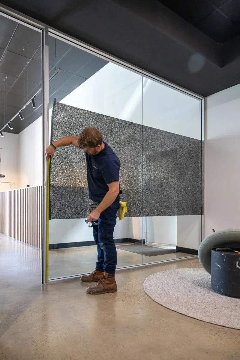 Footprint installer measuring an existing glass partition fitted with decorative film
