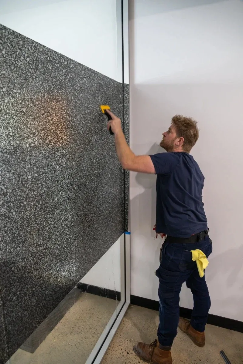 Footprint installer smoothing patterned window film onto office glass