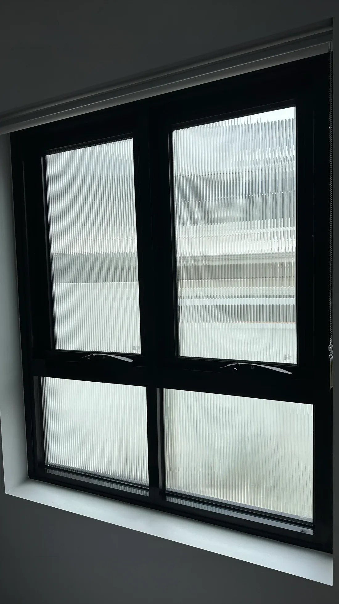 The same black-framed window after reeded film installation, distorting the view of neighbouring buildings