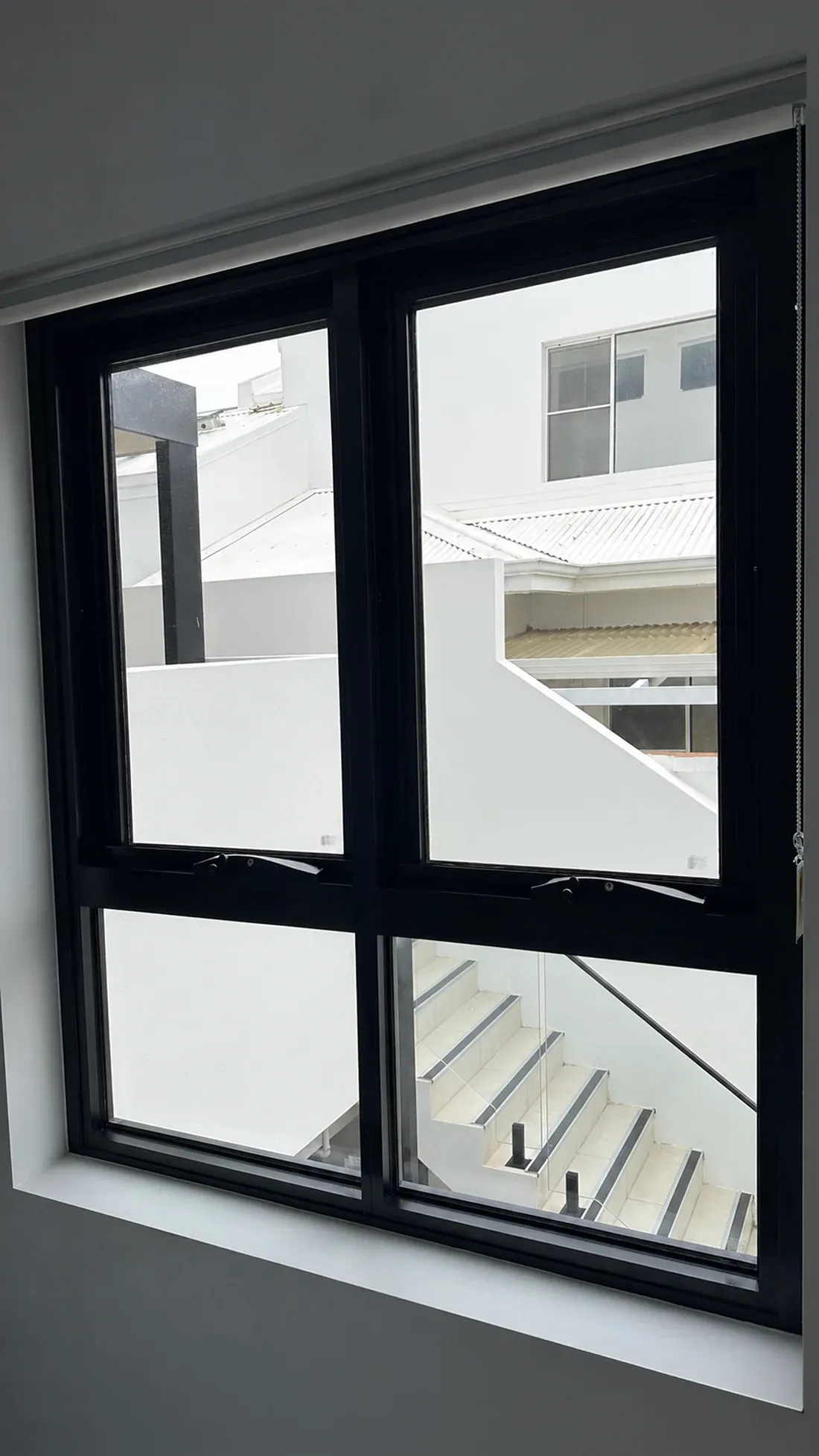 Black-framed window before film installation, with neighbouring buildings clearly visible
