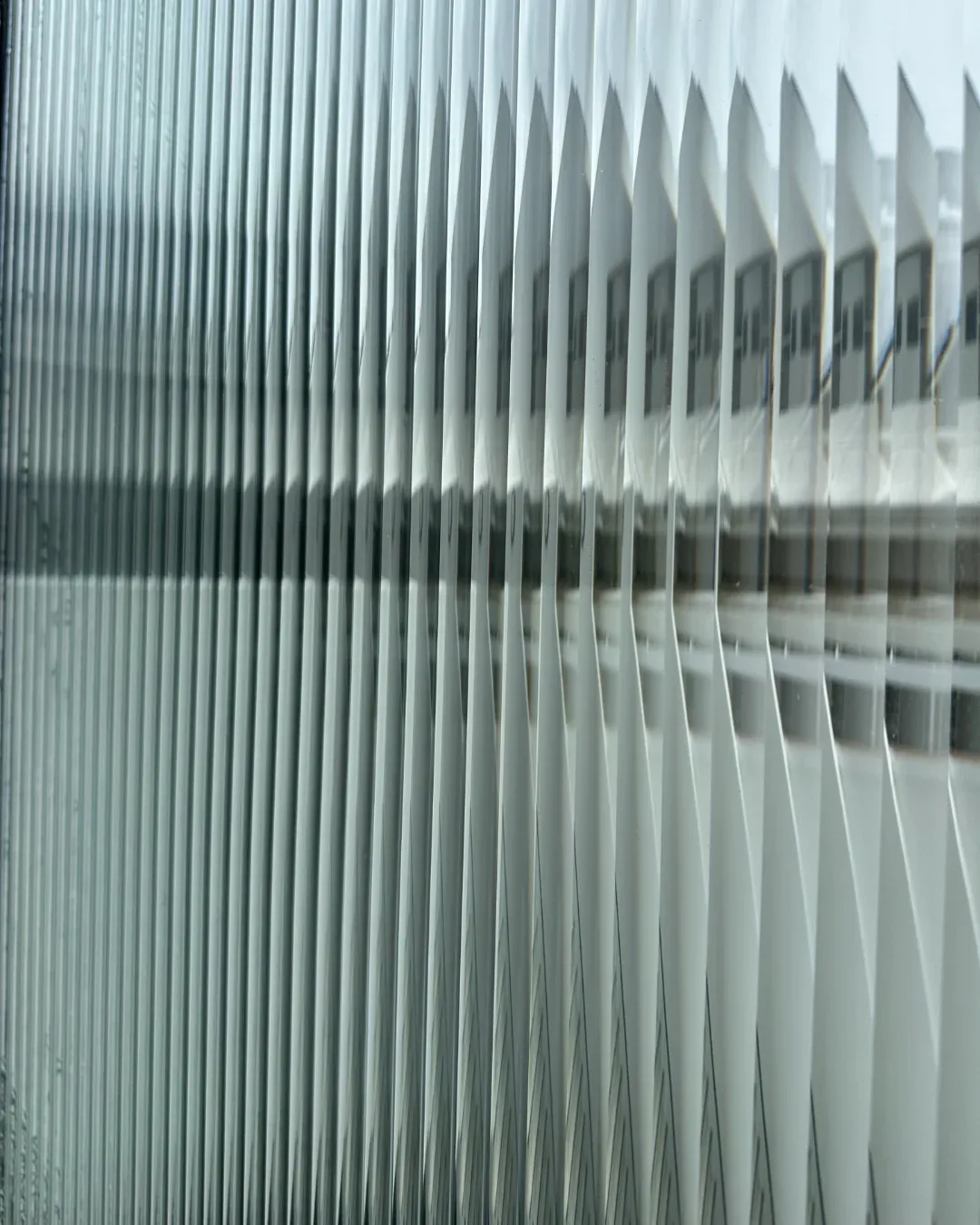 Close-up of the installed reeded film, showing vertical ribs refracting the building beyond